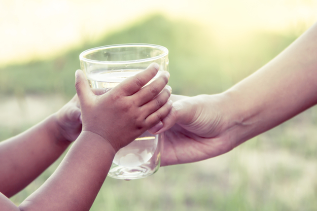parents handing child a glass of water